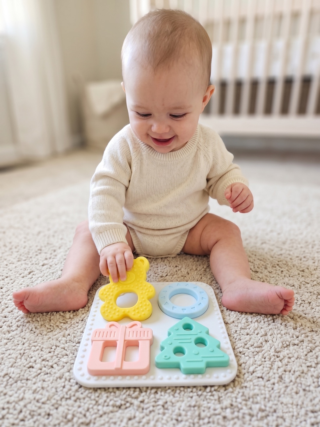 Smiling baby playing with the Babylul teether puzzle on a nursery play mat
